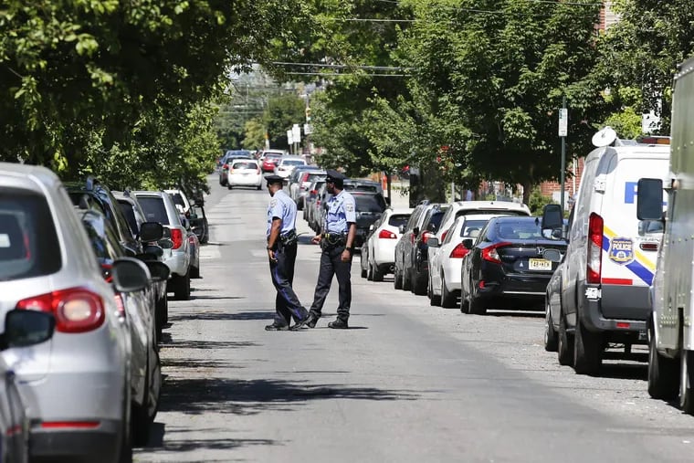 Philadelphia Police officers examine the 1200 block of Fitzwater Street where a 16-year-old boy was killed and a 12-year-old injured in gunfire Friday night.