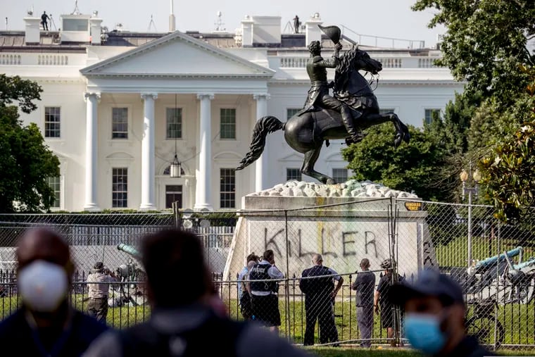 The White House is visible behind a statue of President Andrew Jackson in Lafayette Park in Washington on Tuesday, with the word "Killer" spray-painted on its base. Protesters tried to topple the statue Monday night.