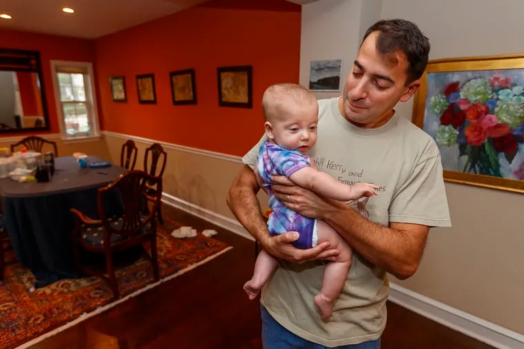 Brian Gralnick, who has De Quervain's tenosynovitis in his right wrist, cradles his daughter, Liv, 6 months old, in his home in Elkins Park on Oct. 1, 2019.