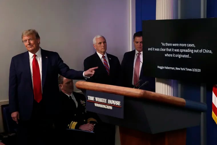 President Donald Trump points as he watches as a White House produced video plays during a briefing about the coronavirus.