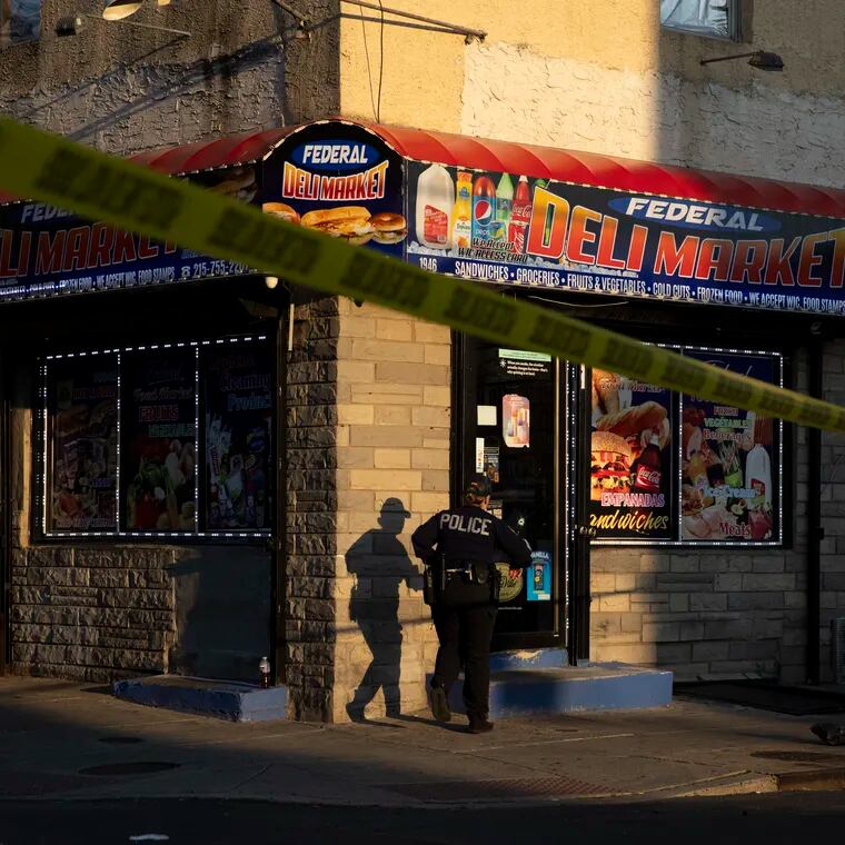 Police stand at the scene of a shooting inside the corner store at 20th and Federal Streets in the Point Breeze section of Philadelphia.