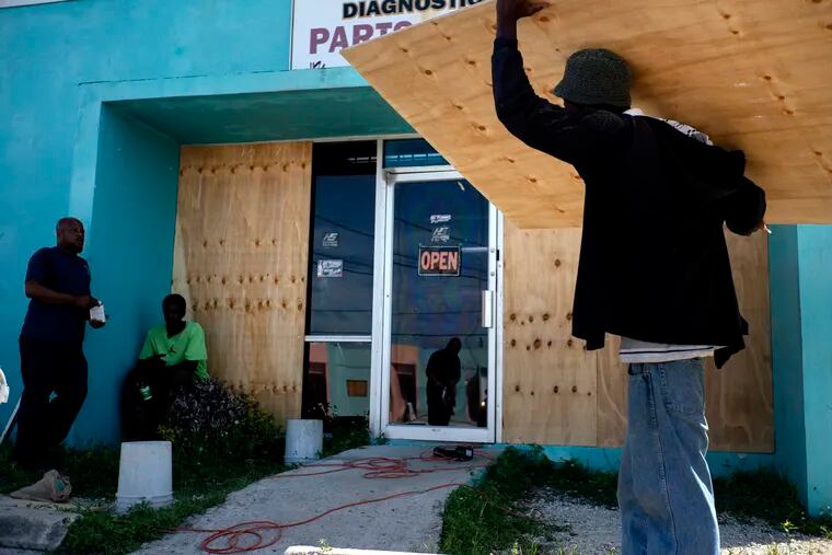 Men protect with wooden boards a shop window from the arrival of Hurricane Dorian in Freeport, Bahamas, Friday, Aug. 30, 2019. (AP Photo / Ramon Espinosa).