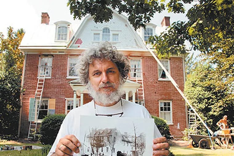 Standing in front of the Haddonfield house, Mark Welsh, holds a photo of the structure from the mid-1800s. He and his son knocked away 10 tons of stucco to get to the original brickwork. (Laurence Kesterson / Staff Photographer)