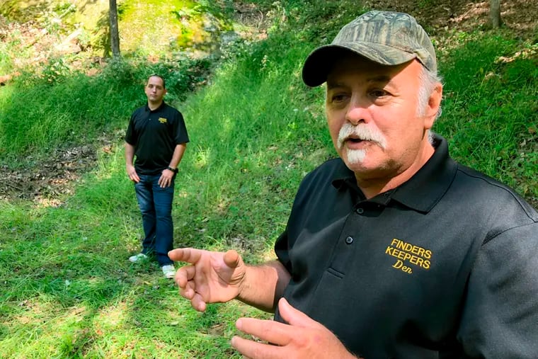 In this Sept. 20, 2018 photo, Dennis Parada, right, and his son Kem Parada stand at the site of the FBI's dig for Civil War-era gold in Dents Run, Pennsylvania. The FBI says the excavation came up empty, but the Paradas believe investigators might have found the legendary gold cache. (AP Photo/Michael Rubinkam)