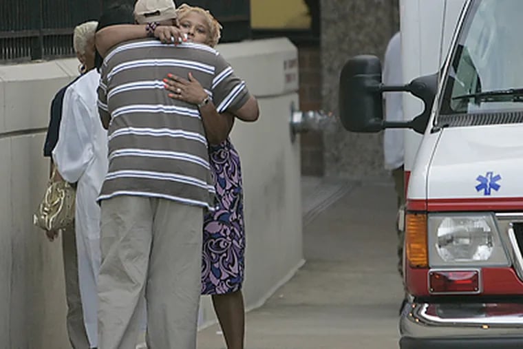 Kathy Caldwell, mother of shot Strawberry Mansion High School graduate Khiry Caldwell, gives a family friend a big hug outside the emergency room at Temple University Hospital. (Michael Bryant/Inquirer)