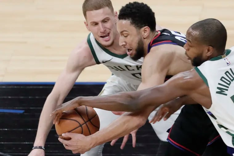 Ben Simmons battles Milwuakee Bucks Donte DiVincenzo (0) and Khris Middleton for the ball in the first quarter of Wednesday's game at the Wells Fargo Center.