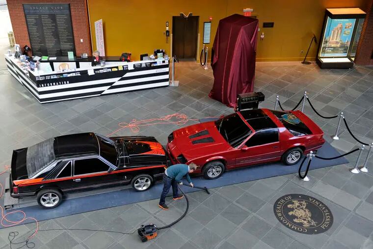 Lee Stoetzel, director of the West Collection, cleans up around artist Jonathan Schipper's &quot;The Slow, Inevitable Death of American Muscle&quot; in SEI Innovation Studio's lobby at the Kimmel Center. The installation is in the new rotating art gallery.