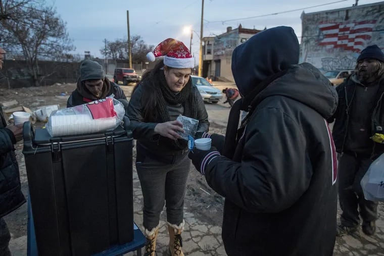 Charito Morales, center, with Homequarters and Friends, passes out hot chocolate and candy to those that ask for it at 2nd and Indiana as part of a holiday program on Monday, Dec. 19.