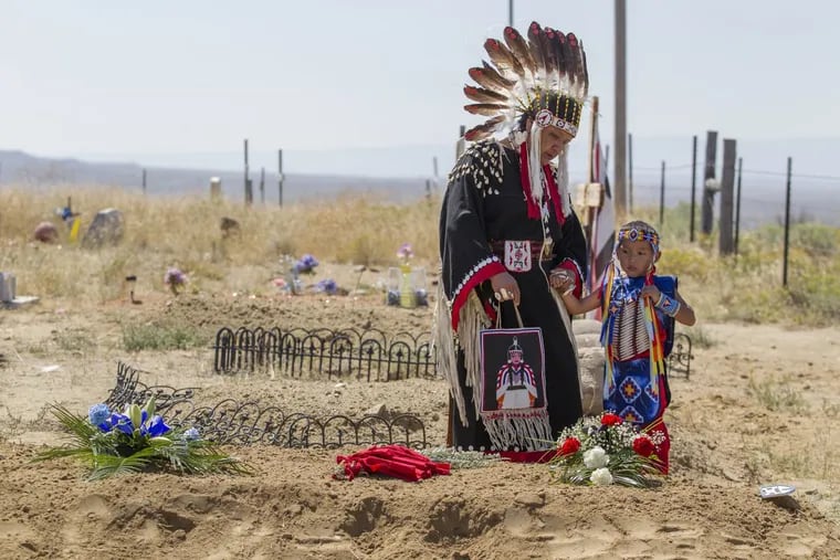 Rae Friday, left, and her grandson, Anthony Michael Enos, pause at the grave of Little Chief (Dicken Nor) at the Sharp Nose Family Cemetery in the Wind River Indian Reservation. They are both descendents of Little Chief. The remains of two Northern Arapaho children, including Little Chief, were disinterred from the Carlisle Barracks Indian Cemetery where they had been buried. They died while attending school there.