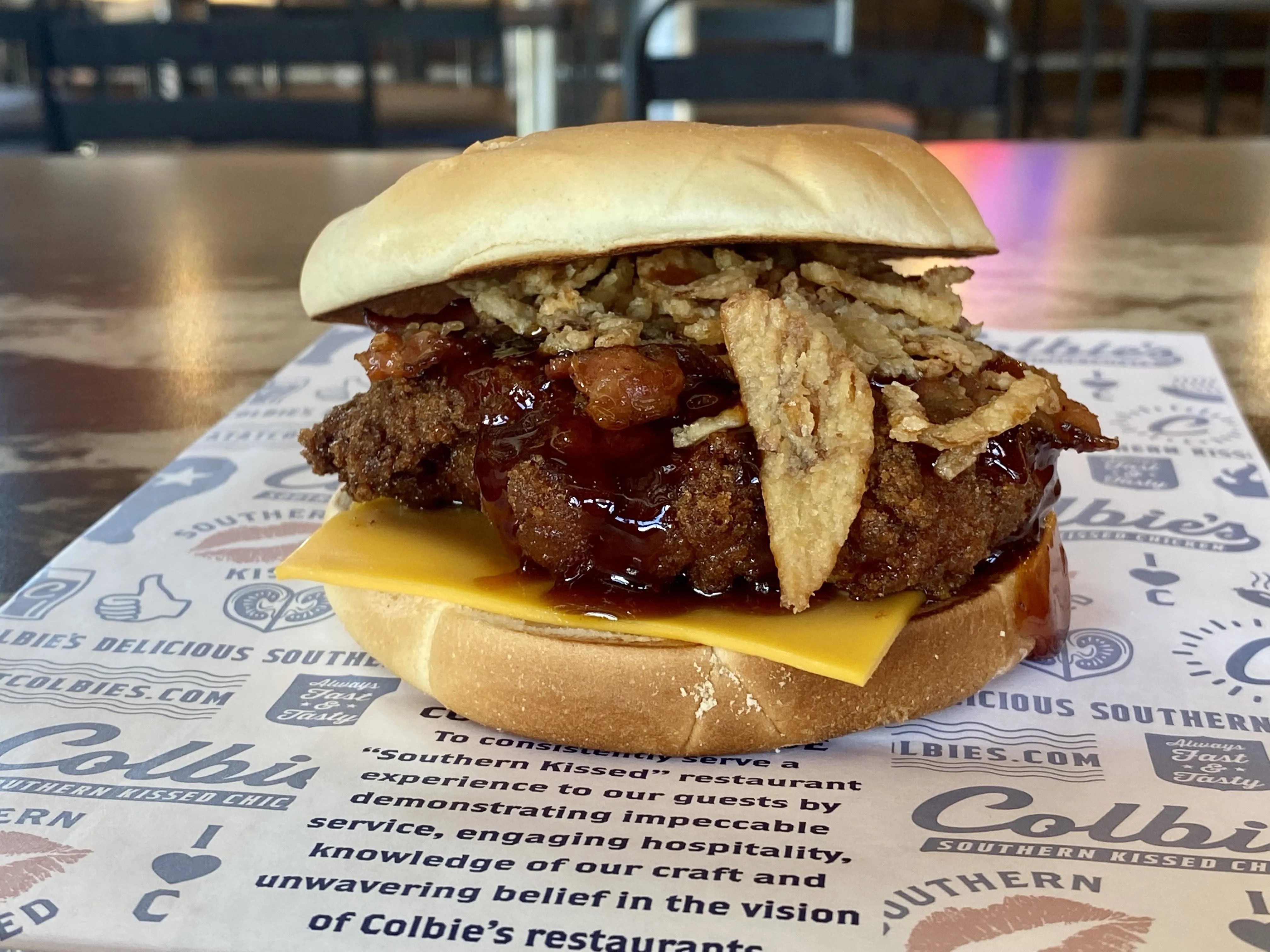 The PBJ Kiss sandwich at Colbie's Southern Kissed Chicken includes peanut sauce, grape jelly, candied bacon, and frizzled onions on a sweet Hawaiian bun.