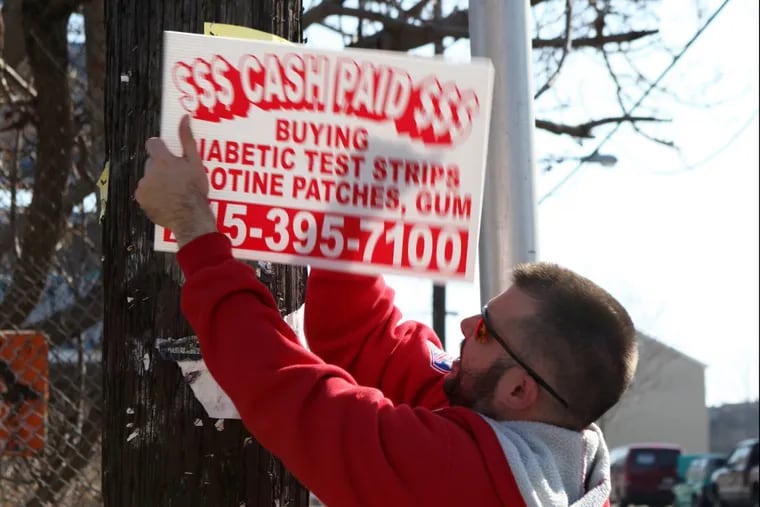 Christopher Sawyer, a vigilante opposing bandit signs, removes a sign at Sixth and Montgomery Streets.