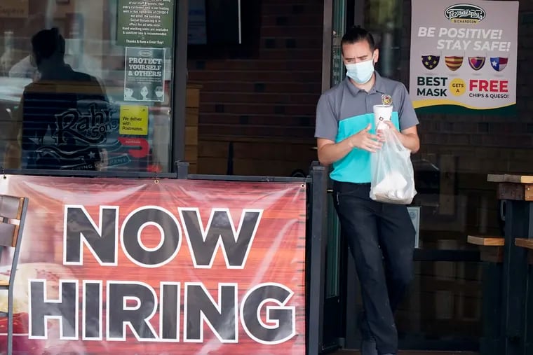 A customer wears a face mask as they carry their order past a now hiring sign at an eatery in Richardson, Texas.  On Thursday, Nov. 5, the number of Americans seeking unemployment benefits fell slightly last week to 751,000, a still-historically high level that shows that many employers keep cutting jobs in the face of the accelerating pandemic.