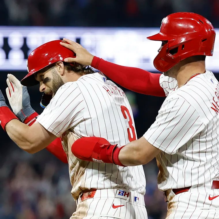 Phillies Bryce Harper celebrates after hitting the game winning sacrifice fly ball in the 10th inning with teammate Whit Merrifield.