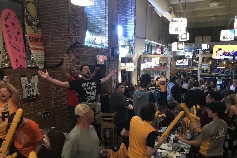 Philadelphia Fusion fans stand on furniture and pound noisemakers together as they celebrate the team's victory over the New York Excelsior at Wahoo's bar and restaurant Saturday, July 21.