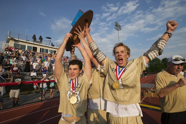 Bishop Shanahan team captains, including Kyle Pollick, left, and C. Tristan Lynch, right, celebrate after being presented PIAA Class 2A boys' lacrosse championship trophy at West Chester East High School on June 9, 2018.