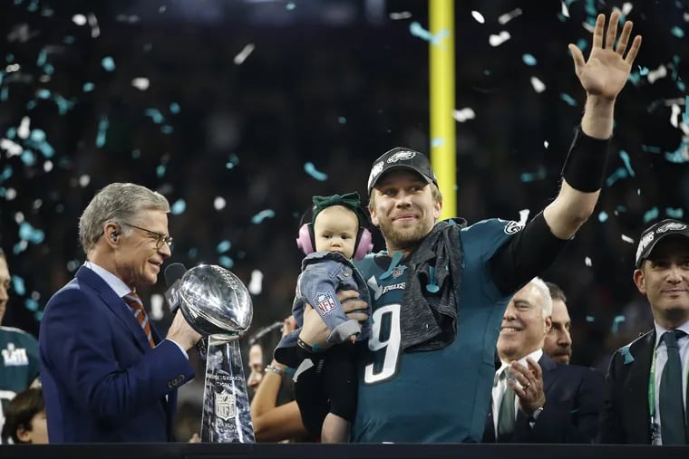 Nick Foles, the Super Bowl LII MVP holds onto his daughter Lily James Foles, and aknowledges the crowd from the vicotry platform after he and his team defeated the New England Patriots.<br/>
MICHAEL BRYANT/ Staff Photographer