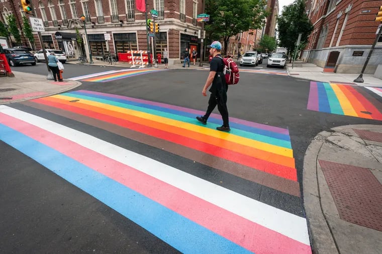Pedestrians walk across a refreshed set of rainbow crosswalks, installed by the city over the weekend, at 13th and Locust Streets.