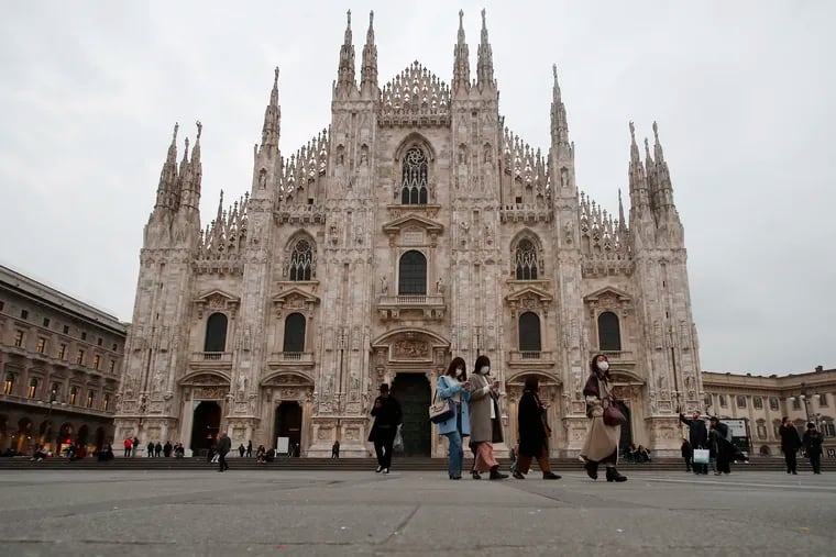 Women wearing face masks walks past the Duomo gothic cathedral in Milan, Italy.