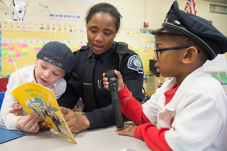 Camden County Police Officer CaBria Davis, 31, reads a book to kindergartners Jayden Martinez (left) and Quinton Gideon at Sumner Elementary School in Camden.