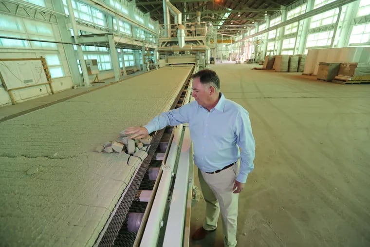 Thomas McGrath, president of AeroAggregates, samples the foamed glass aggregate after it emerges from a kiln, where it is made from recycled glass bottles.The company has installed a second kiln, doubling production.