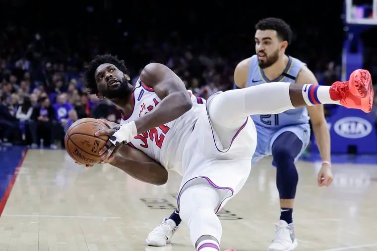 Sixers center Joel Embiid falls back as he grabs the ball in front of Memphis Grizzlies guard Tyus Jones in the first quarter on Friday, Feb. 7, 2020.