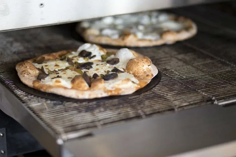 A pizza comes out of the oven at Snap Custom Pizza in Conshohocken. Snap opened its sixth location July 25.