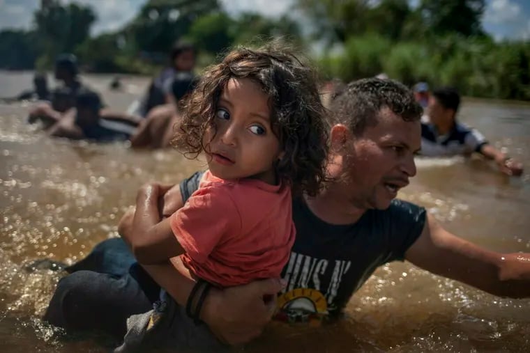 In this Oct. 29, 2018, photo taken by Reuters photographer Adrees Latif, Luis Acosta carries 5-year-old Angel Jesus, both from Honduras, as a caravan of migrants from Central America en route to the United States crossed through the Suchiate River into Mexico from Guatemala in the outskirts of Tapachula. A team of Reuters photographers won the Pulitzer Prize in breaking news photography for their coverage of migrants as they journeyed to the U.S. from Central and South America.