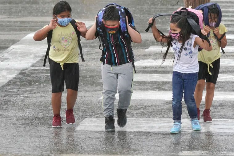 Elementary school children wear masks as they make their way across the street after school let out during a rain storm in Richardson, Texas.