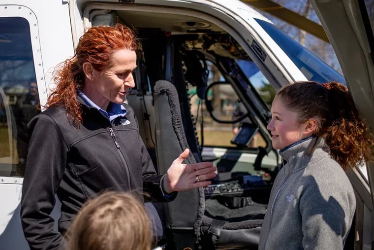 Pilot Kim Barwick shows Hailey Shapiro the inside of a Sikorsky helicopter after she landed it outside Phoenixville Area Middle School Saturday in a dramatic kickoff of the 19th annual Girls Exploring Tomorrow's Technology event.