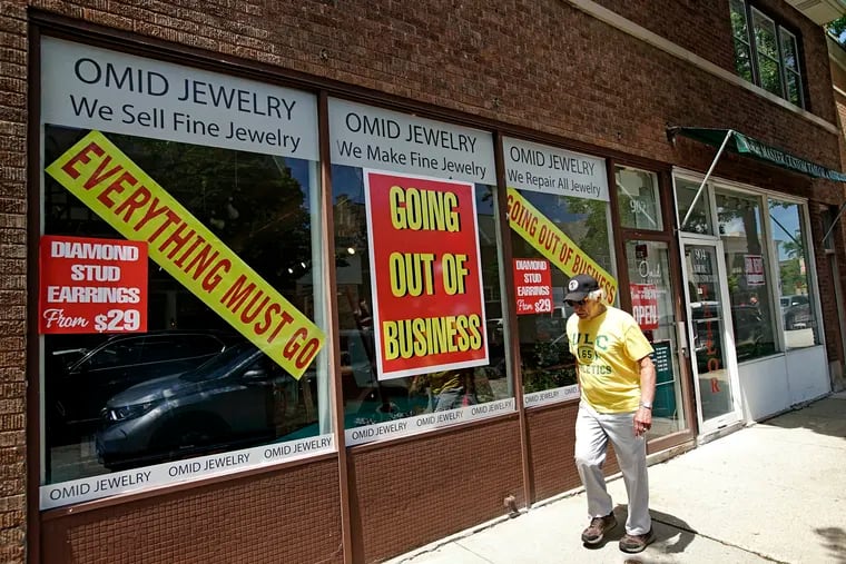 A man walks past a retail store that is going out of business because of the coronavirus pandemic in Winnetka, Ill.
