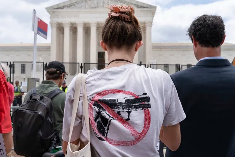 A woman wears an anti-gun T-shirt outside of the Supreme Court, following the Supreme Court's decision to overturn Roe v. Wade in Washington, Friday, June 24, 2022. The Supreme Court on Thursday struck down a New York state law that had restricted who could obtain a permit to carry a gun in public.