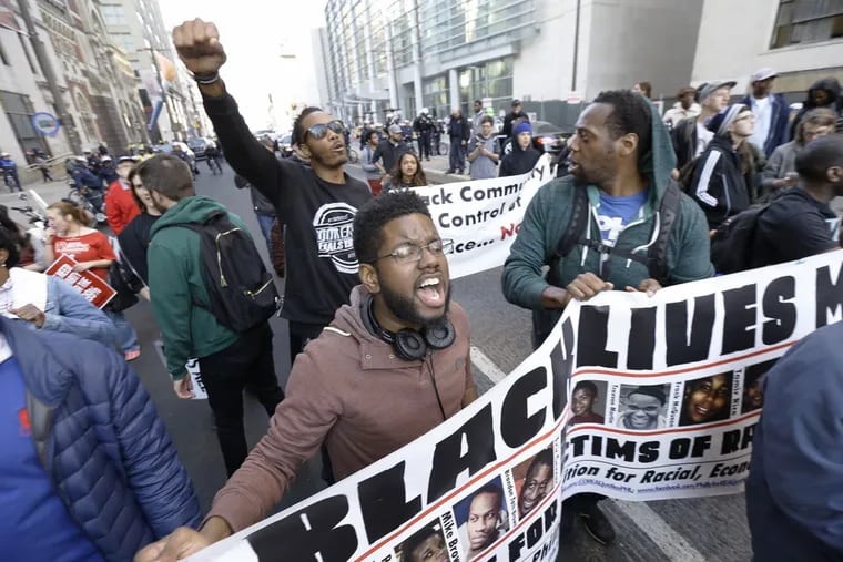 Anthony Smith of the Philadelphia Coalition for Real Justice shouts as he and a fellow demonstrator hold a Black Lives Matter banner at Broad and Arch Streets. Theirs was one of several contingents protesting.