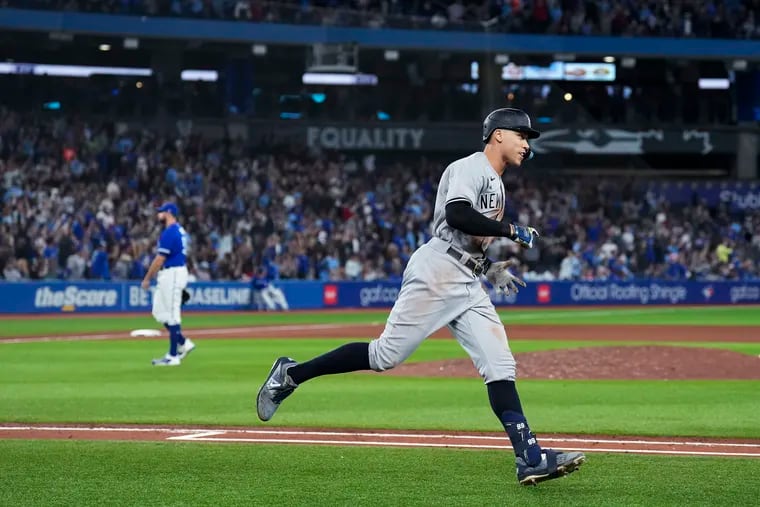 Aaron Judge runs the bases after hitting his 61st home run, off Toronto Blue Jays pitcher Tim Mayza, left.