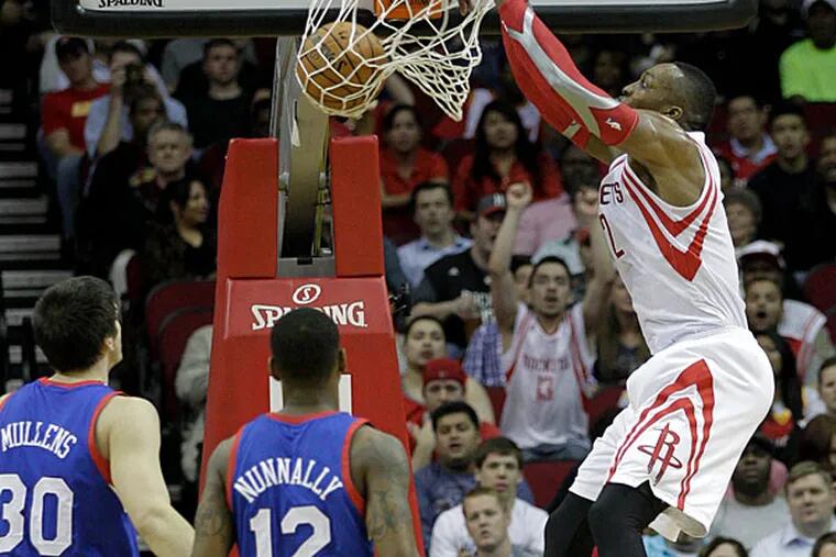 Dwight Howard, right, dunks over Philadelphia 76ers' James Nunnally (12) and Byron Mullens (30) during the first half of an NBA basketball game on Thursday, March 27, 2014, in Houston. (Bob Levey/AP)