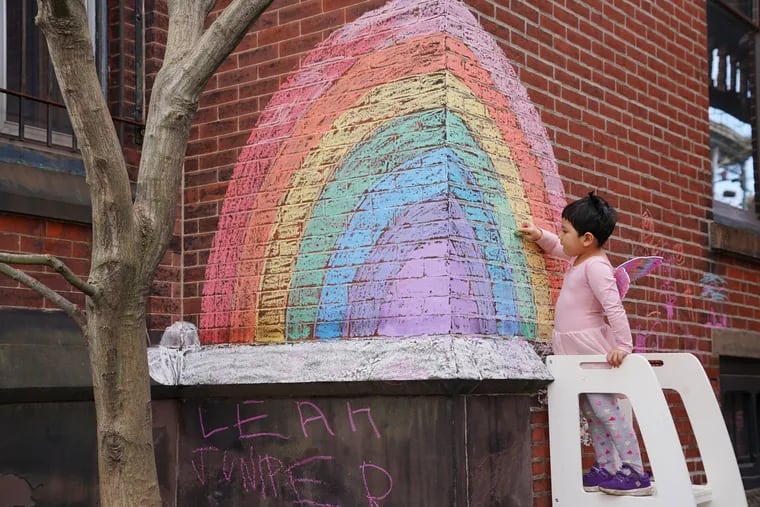 Four-year-old Juniper Assis Finlayson colors in blank spots with chalk on a rainbow she and her Mom drew earlier in the week on Tuesday, in Philadelphia, March 27, 2020. Juniper also enjoys going for walks with her mom's and participating in the rainbow scavenger hunt around 26th and Poplar Streets.
