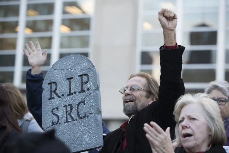 Douglas Leach, a graduate and now a teacher at Lincoln High School, holds a tombstone for the SRC as they rally outside the School District of Philadelphia Building on Nov. 16, 2017. The School Reform Commission took a historic vote to self-destruct. What happens next is something Philadelphians should pay close attention to in 2018.