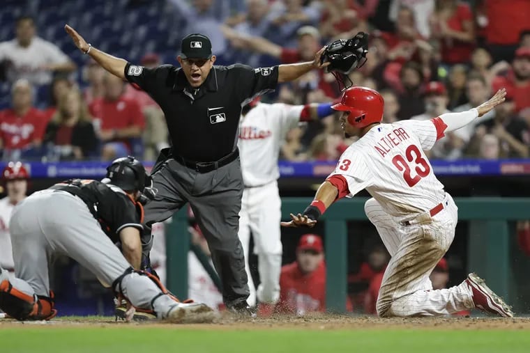 Aaron Altherr signals he's safe — and umpire Alfonso Marquez agrees — after sliding past the tag of Marlins catcher J.T. Realmuto during Friday's win.