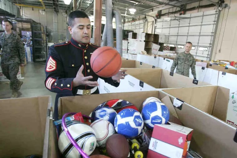 Staff Sgt. Marc Palos , coordinator of the effort here, looks over donations. This year, 90,000 toys were collected. Registered charities can apply for up to 300 toys, one toy per child.
