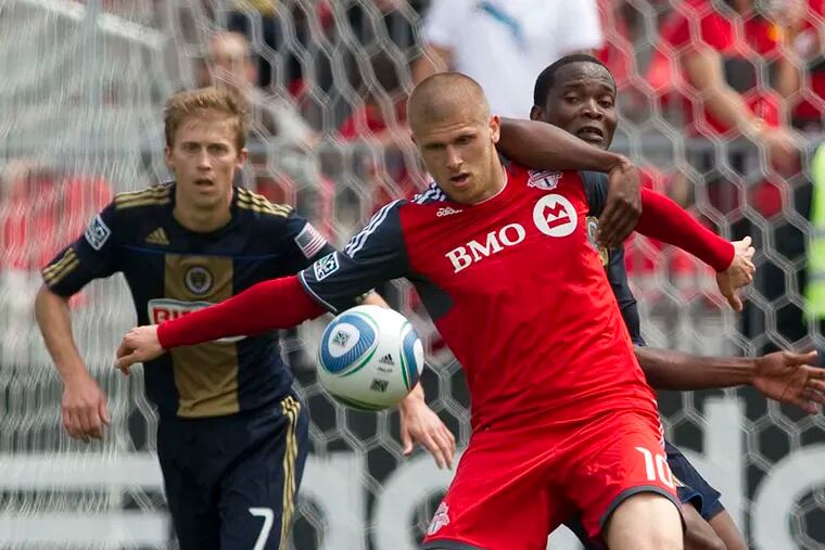 Toronto FC's Alen Stevanovic (center) holds off Philadelphia Union's Danny Mwanga as Union's Brian Carroll (7) looks on during the second half. (AP Photo/The Canadian Press, Chris Young)