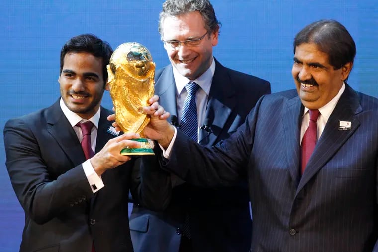 Mohamed bin Hamad Al-Thani (left), chairman of Qatar's 2022 World Cup bid committee, and Sheikh Hamad bin Khalifa Al-Thani, Emir of Qatar, hold the men's World Cup trophy in front of FIFA Secretary General Jerome Valcke after the announcement on Dec. 2, 2010, that Qatar will host the 2022 tournament.