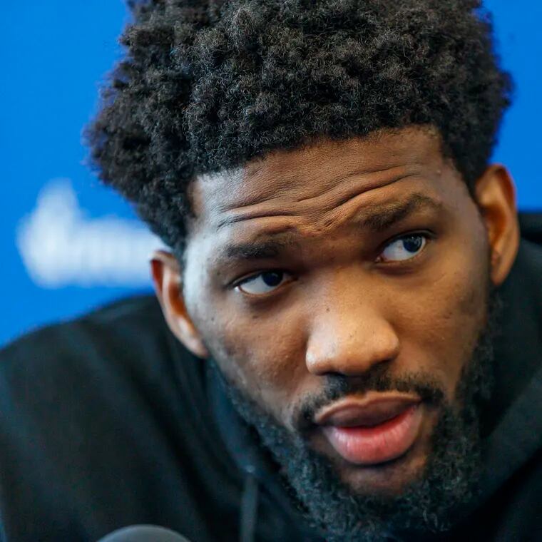 Joel Embiid listens to a question during a press conference.