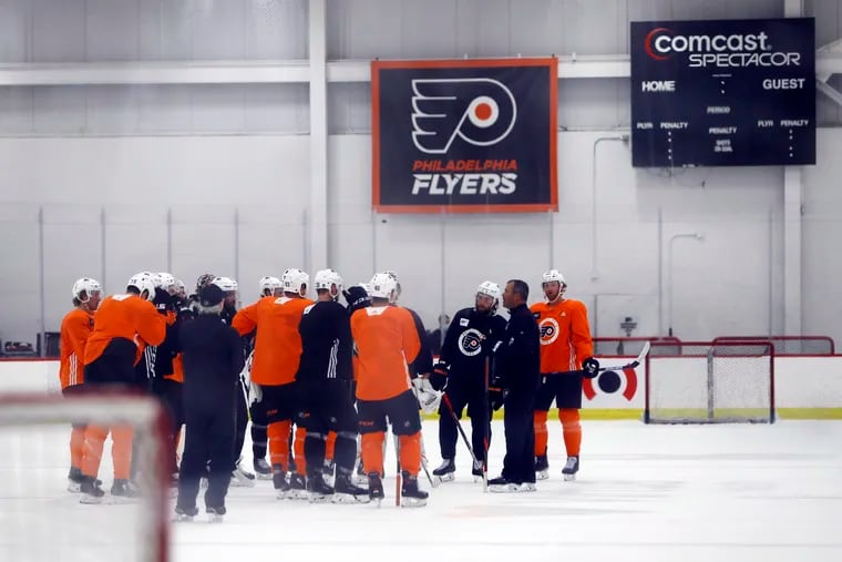 Flyers players gather with head coach Alain Vigneault during training camp at their Voorhees practice facility Monday.