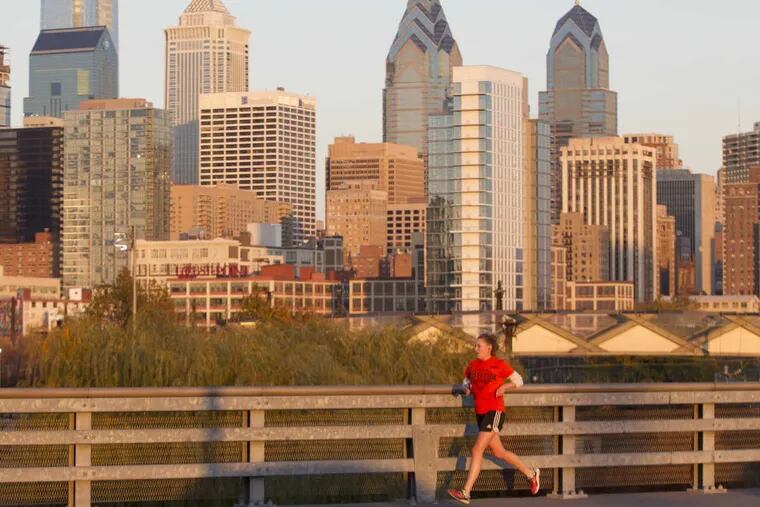 A jogger on the South St. Bridge on Nov.17, 2016 with the city bathed in the light of the setting sun.