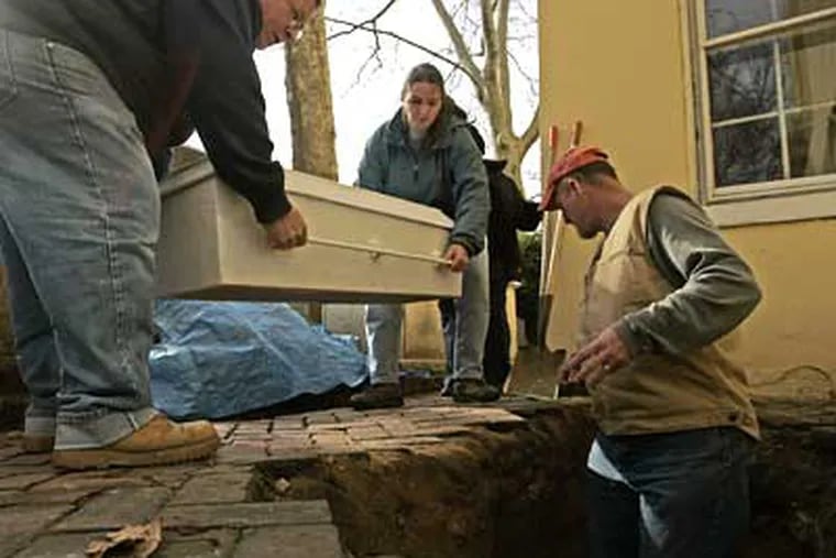 Joe Tursi (left) and Kimberly Morrell carry a casket with the remains of the Rev. Stephen Gloucester, his wife Ann and David Winrow, while archaeologist Douglas Mooney waits in the grave site at the Old Pine Cemetery. ( Michael Perez / Staff Photographer )