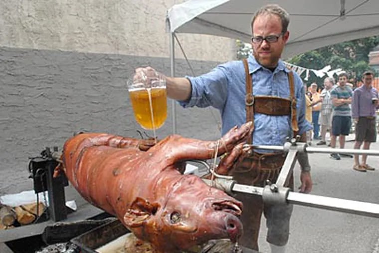 On Spring Garden Street, Jeremy Nolen pours beer on a pig on a spit. ( April Saul / Staff Photographer )