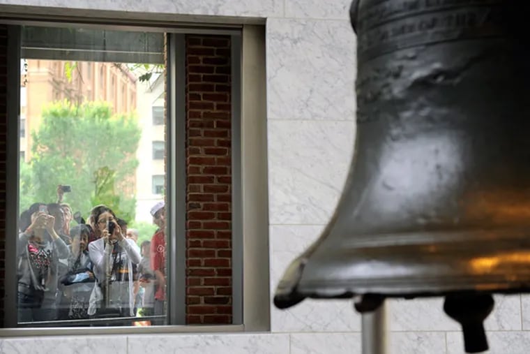 Visitors to Independence National Park take photos of the Liberty Bell July 4, 2014, through a window from outside.