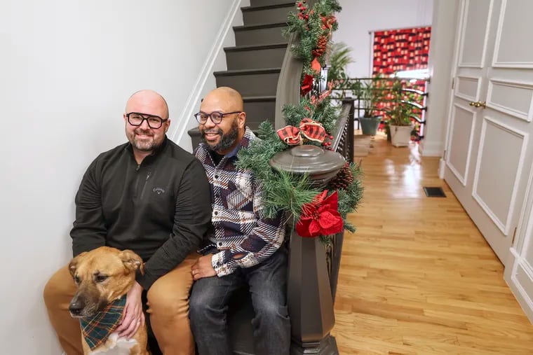 Jeffrey Keyes, left, and Desmond Patton pose for a portrait along with their dog Jesse inside their Brewerytown home in Philadelphia on Friday, Dec. 1, 2023.