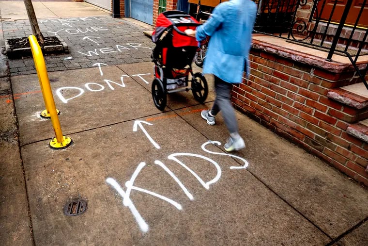 A graffiti message is spray painted on a sidewalk near Meredith Elementary School in South Philadelphia Wednesday. Other graffiti on school property at the school and at the nearby Nebinger Elementary were removed by the school district. Philadelphia public schools temporarily returned to mandatory masking after the winter break. (The complete message reads “kids don’t wear your mask!”)