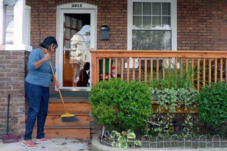 Diane Valentine Bey sweeps outside her home October 7, 2014. Her Sandy-damaged porch was replaced by the Atlantic City Long Term Recovery Group. ( TOM GRALISH / Staff Photographer )