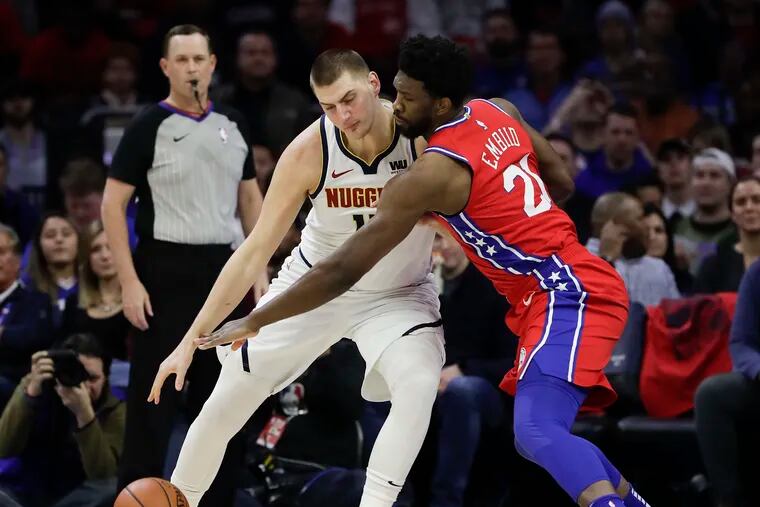 Sixers center Joel Embiid reaching for the ball against Nuggets center Nikola Jokic during a game in February.
